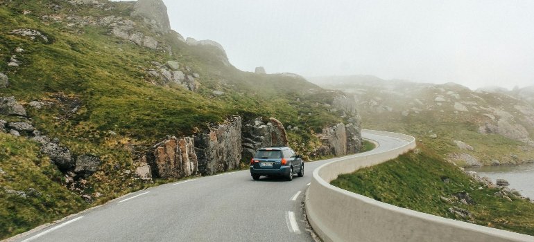 Car driving on road among rocky mountains