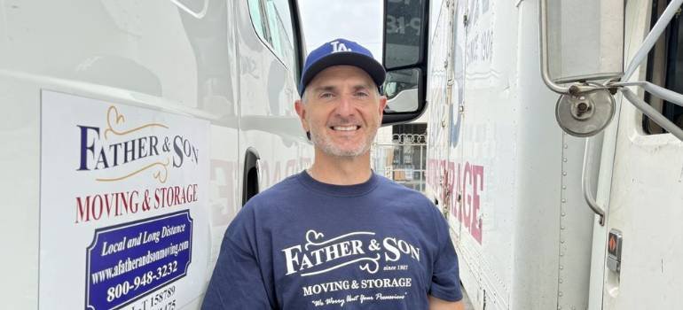 one of our long distance movers los angeles based standing next to A Father and Son moving trucks