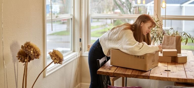 woman packing a box near a bright window