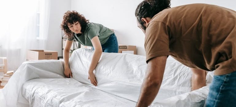 Couple Wrapping A Couch With White Cloth