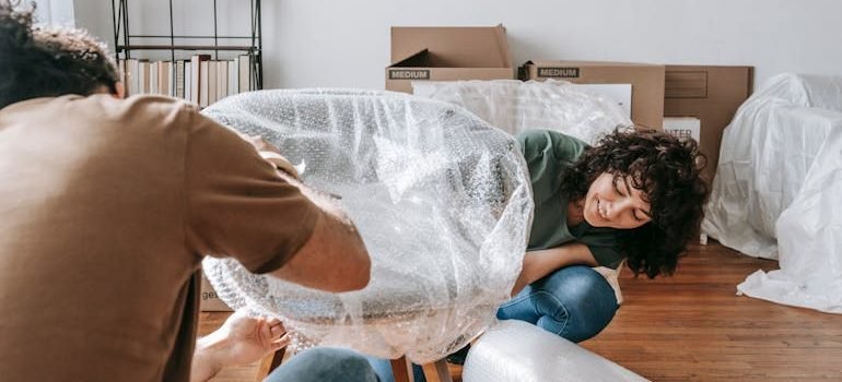Couple Wrapping A Chair With Plastic