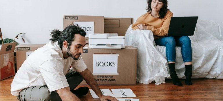 Man checking labeled boxes while following tips for moving out for the first time.