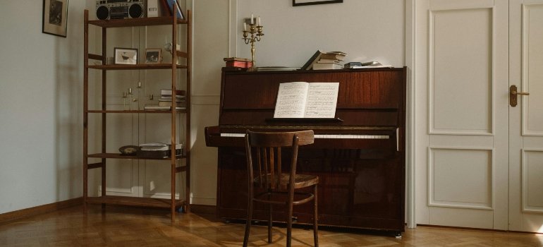 Wooden Piano and Chair Near White Wall