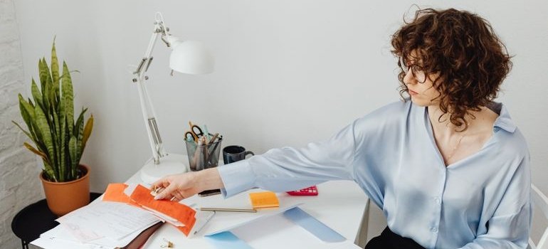 a woman sorting mail and envelopes at a desk during a change of address checklist
