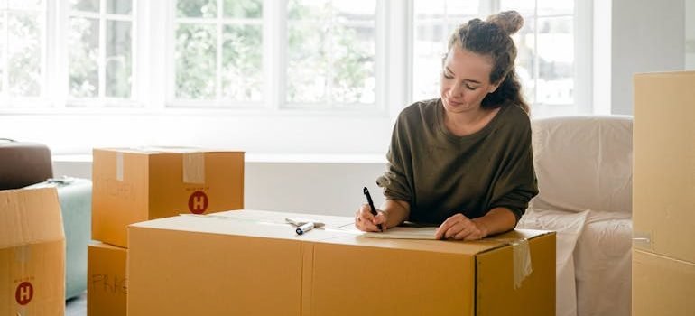 Woman signing box near large window in sunlight at home