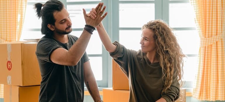 couple giving high give standing near pile of boxes