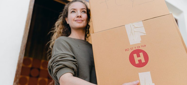 Encino apartment living with a woman carrying moving boxes outside a home