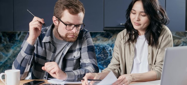 A Couple Looking at a Paper on a Desk with a Calculator