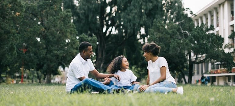 Family Sitting on Grass Near Building