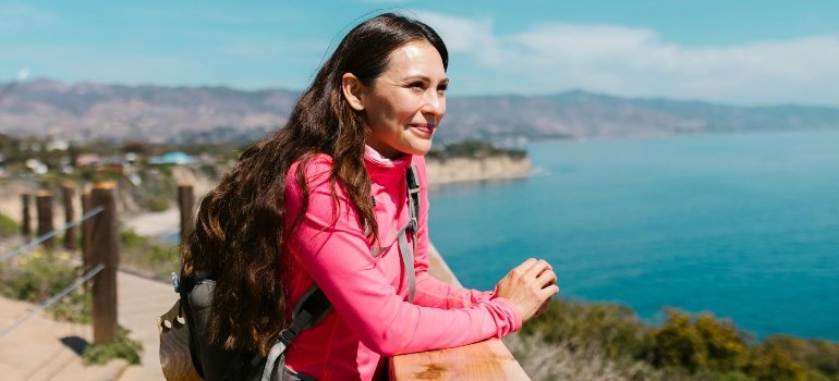 Woman in pink jacket standing on a brown wooden dock