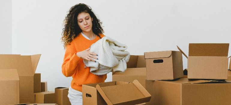 Focused young relocating female packing belonging into cardboard boxes for moving with reseda movers ca