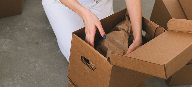 a woman relying on tips for moving across the country to pack a large brown moving box