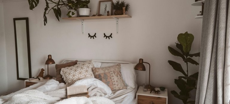 Photo of lamp beside bed with pillows, representing comfort and essentials from a college packing list.