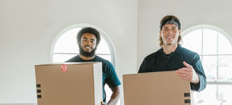 Two reliable movers holding boxes during a residential move